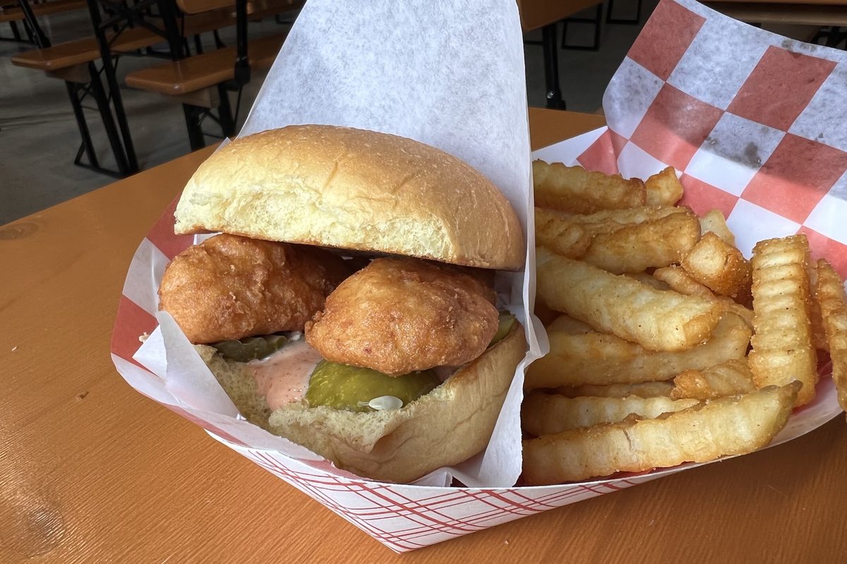 A fried chicken sandwich with pickles and crinkle fries in a checkered boat